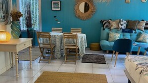 A room with teal walls, a dining area with a table and chairs, a sofa with patterned cushions, and hanging wicker lamps. - Villa Entre Pinède et Calanques de Marseille, 6 Chambres, 12 Couchages, Piscine (Marseille)