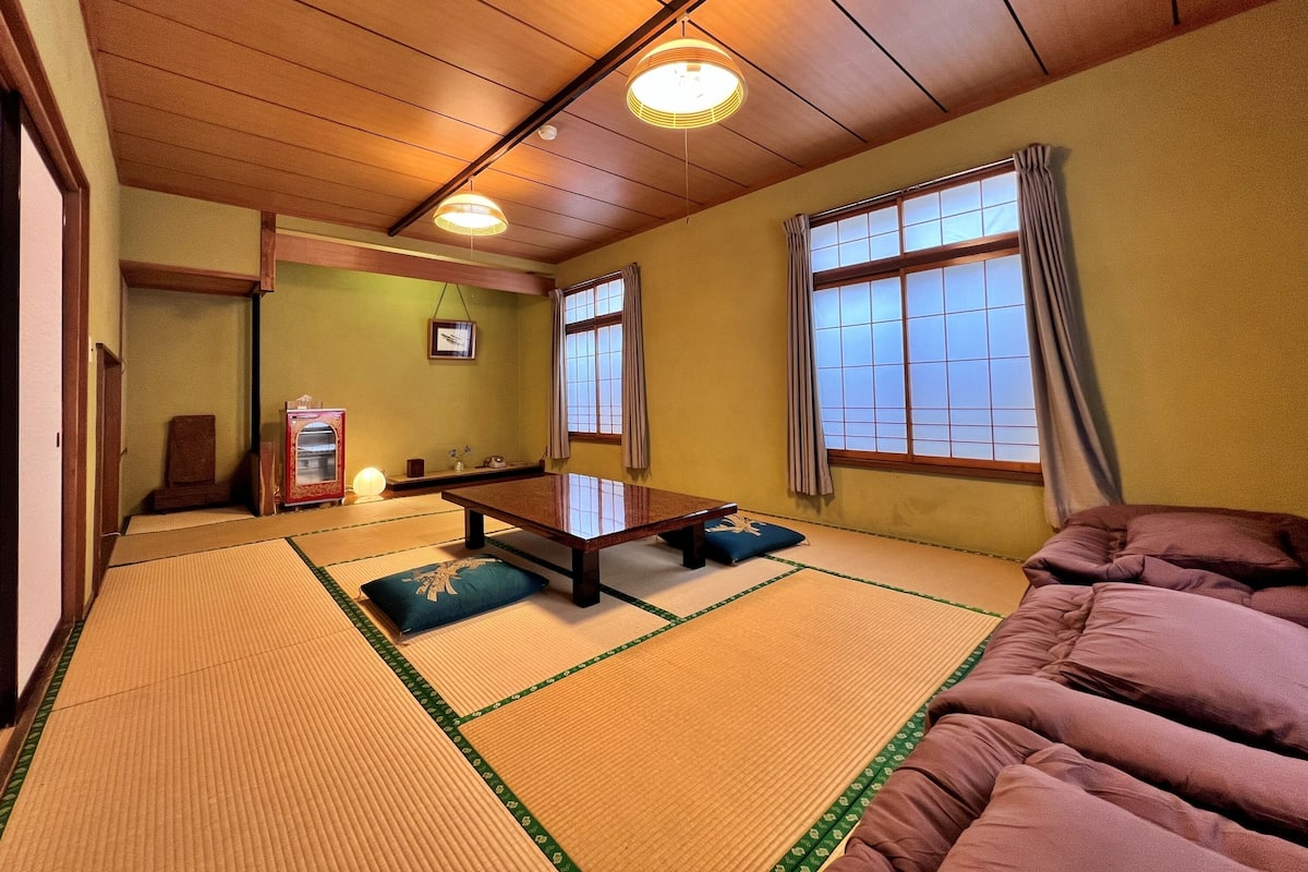 Ein traditioneller japanischer Raum mit Tatami-Böden, einem niedrigen Tisch, Kissen und Schiebetüren.