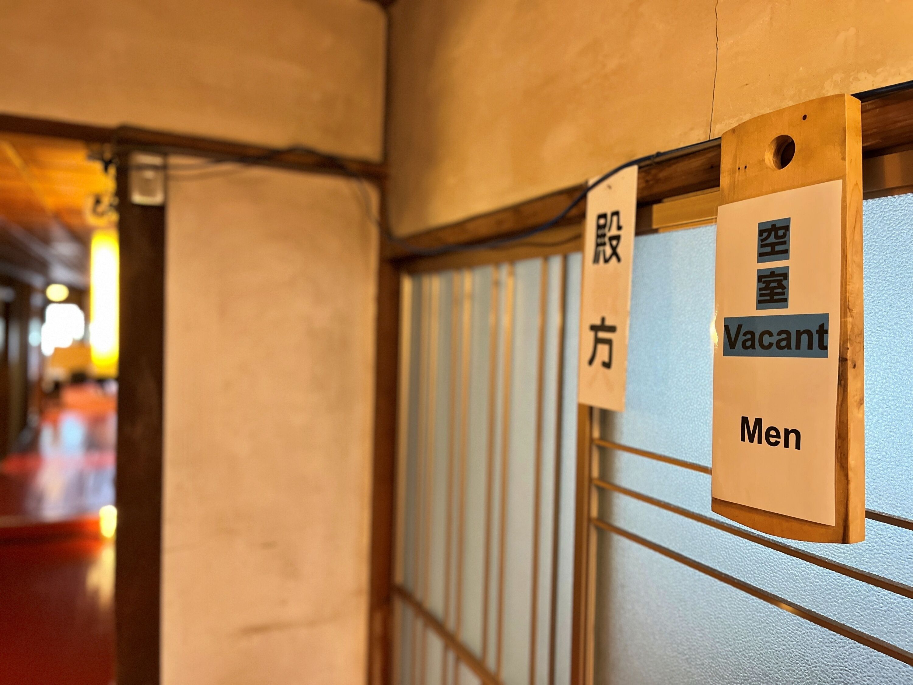 A hotel corridor with signs indicating a vacant men's room.