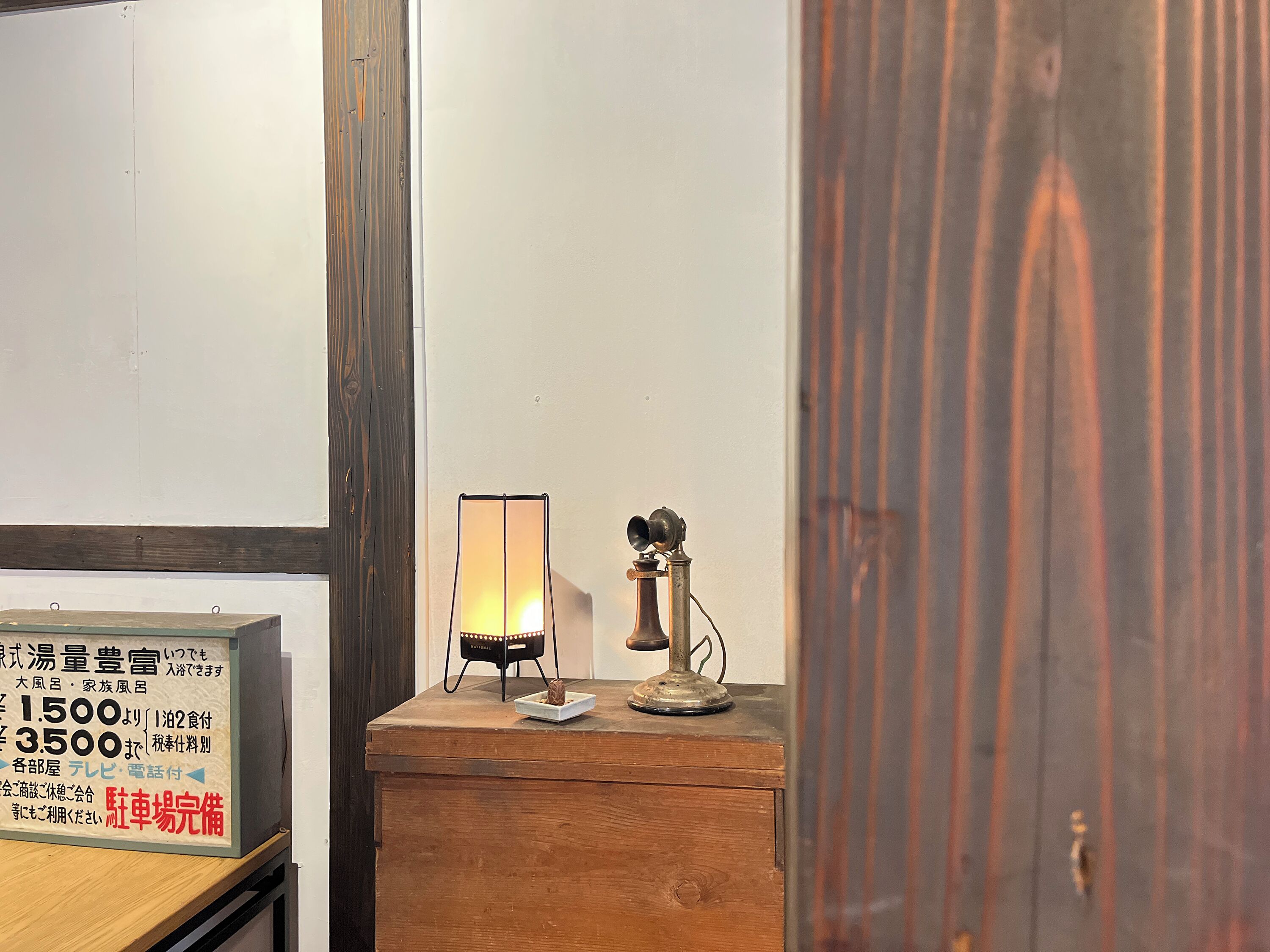 Un mueble de madera con un teléfono antiguo y una lámpara de mesa.