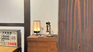 Un mueble de madera con un teléfono antiguo y una lámpara de mesa.