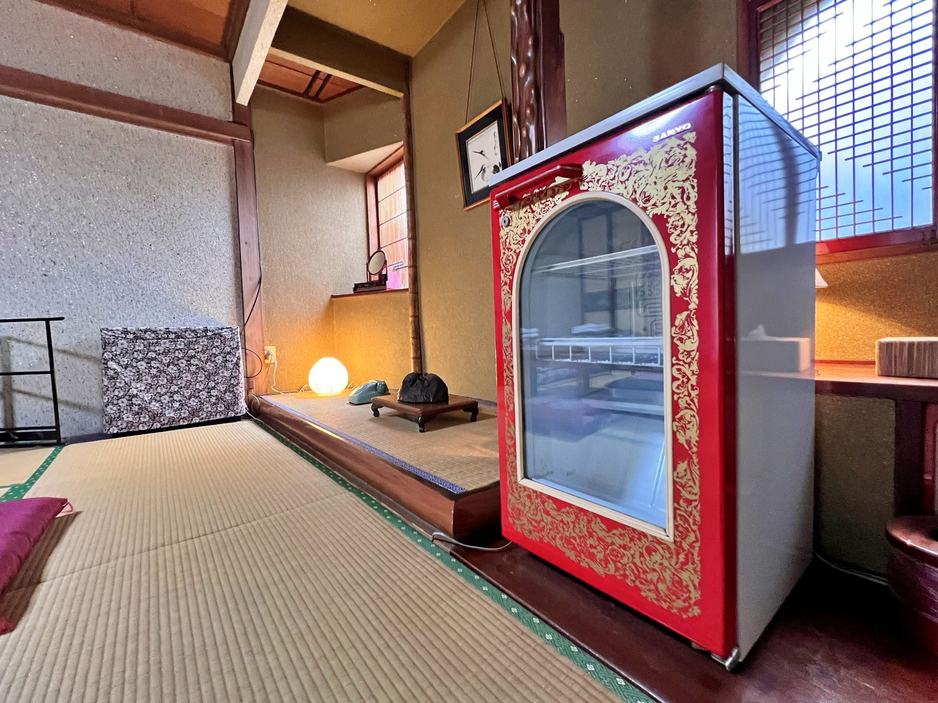 A traditional Japanese room with tatami flooring, a red and gold cabinet, and a sliding door.