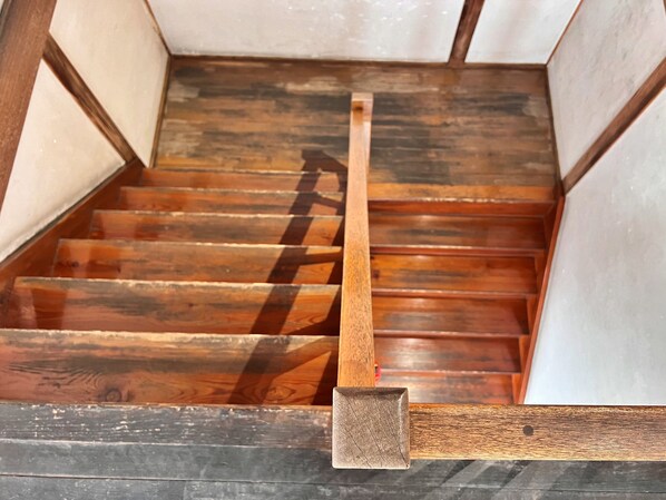 Una escalera de madera con barandilla y piso oscuro.