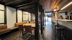 A modern interior with a wooden ceiling, a long dining table, and bar stools.