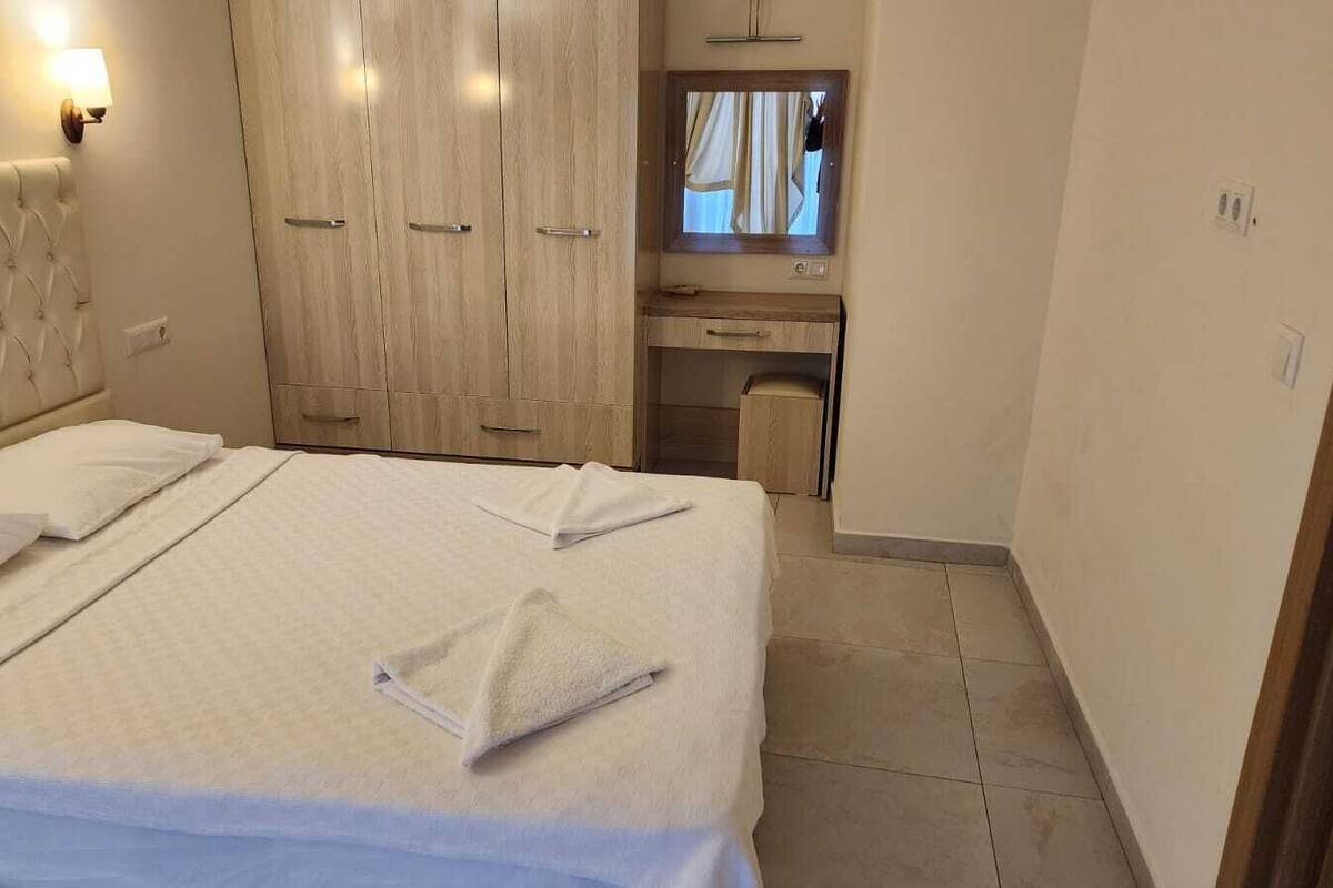 A hotel room with a bed, a wardrobe, a desk, and a mirror.