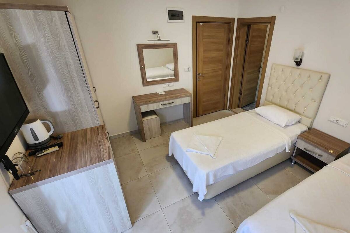 A hotel room with a bed, a desk, a chair, a TV, and a wardrobe.