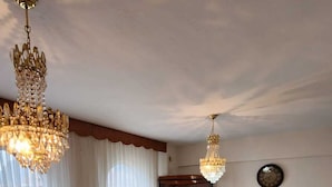 A living room with a sofa, a coffee table, a chandelier, a cabinet, and a television. - Can Motel (Marmaris)