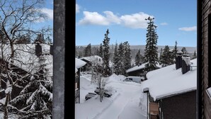 A snowy landscape with a clear sky, trees, and buildings.