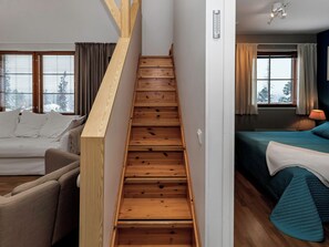 A wooden staircase leading to a bedroom with a bed and a window.