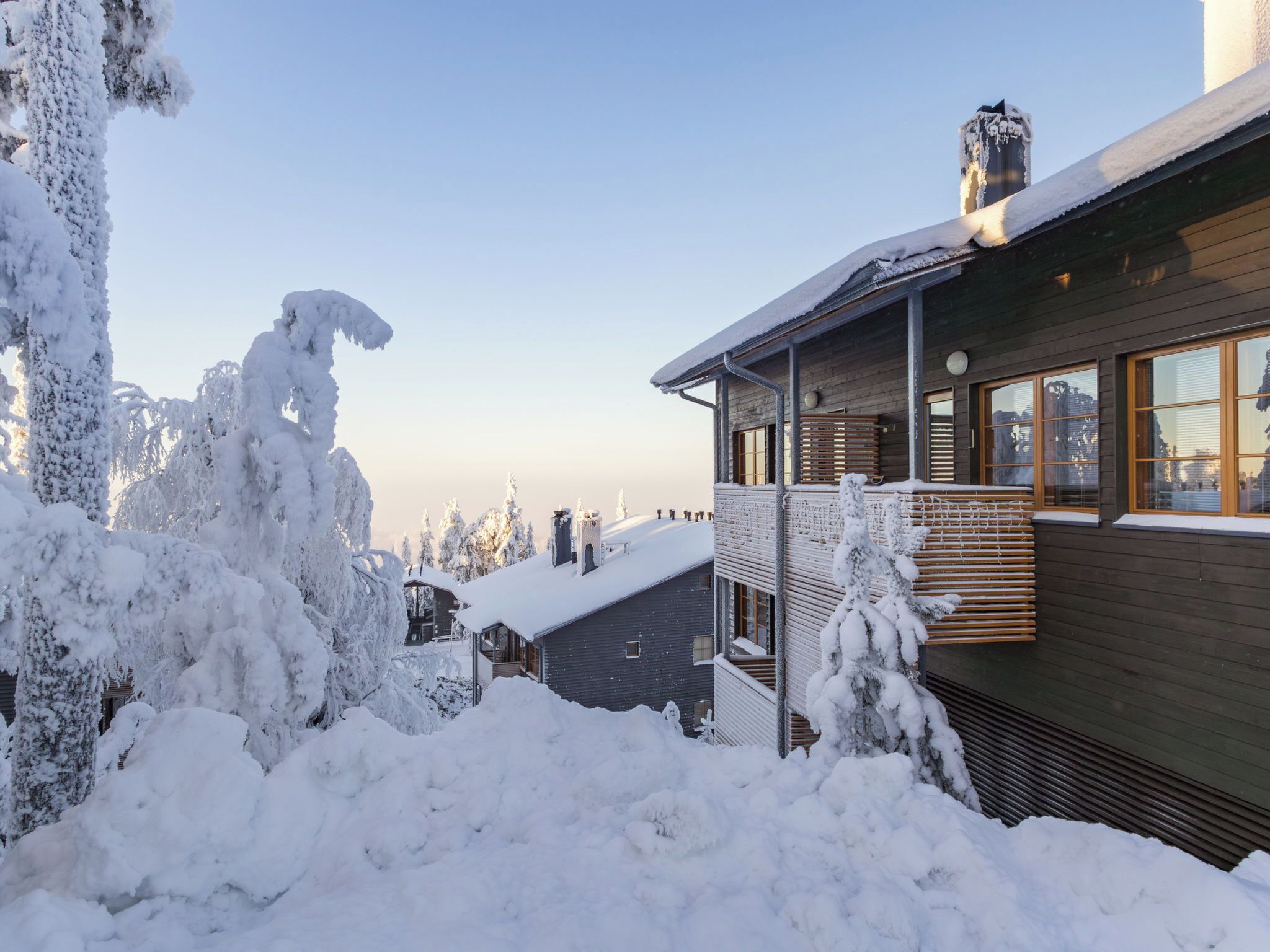 Une maison moderne avec une façade en bois, de grandes fenêtres et un balcon.