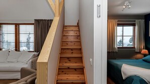 A staircase leading to a bedroom with a bed, a sofa, and a window with curtains.
