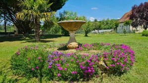 Un giardino con una fontana in pietra al centro, circondata da fiori colorati.