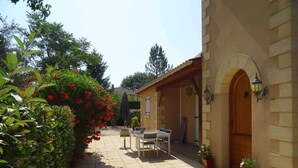 Un cortile con pavimento in piastrelle, una porta in legno e un tavolo con sedie.