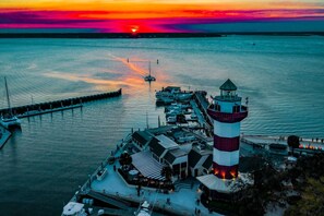 A waterfront area with a lighthouse, docked boats, and a pier extending into the water.