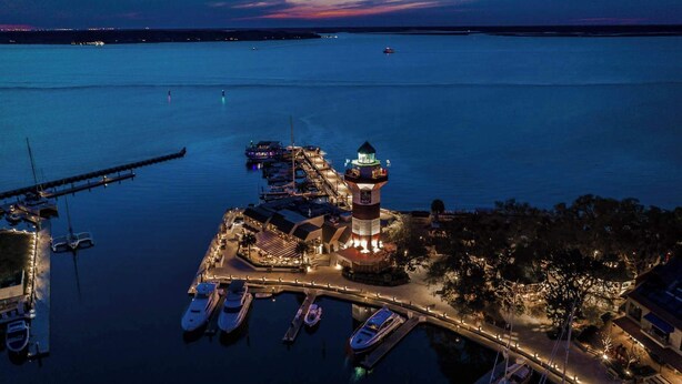 A marina with boats docked, a lighthouse, and a pier extending into the water. - Fairway One Villa Golf & Lagoon Views Walk to Beach Club (Hilton Head Island)