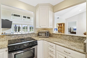 A kitchen with white cabinets, a granite countertop, a built-in oven, and a microwave. - Fairway One Villa Golf & Lagoon Views Walk to Beac (Hilton Head Island)