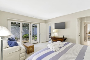 A hotel room with a bed, a desk, a chair, a television, and a sliding glass door leading to a balcony. - Fairway One Villa Golf & Lagoon Views Walk to Beac (Hilton Head Island)