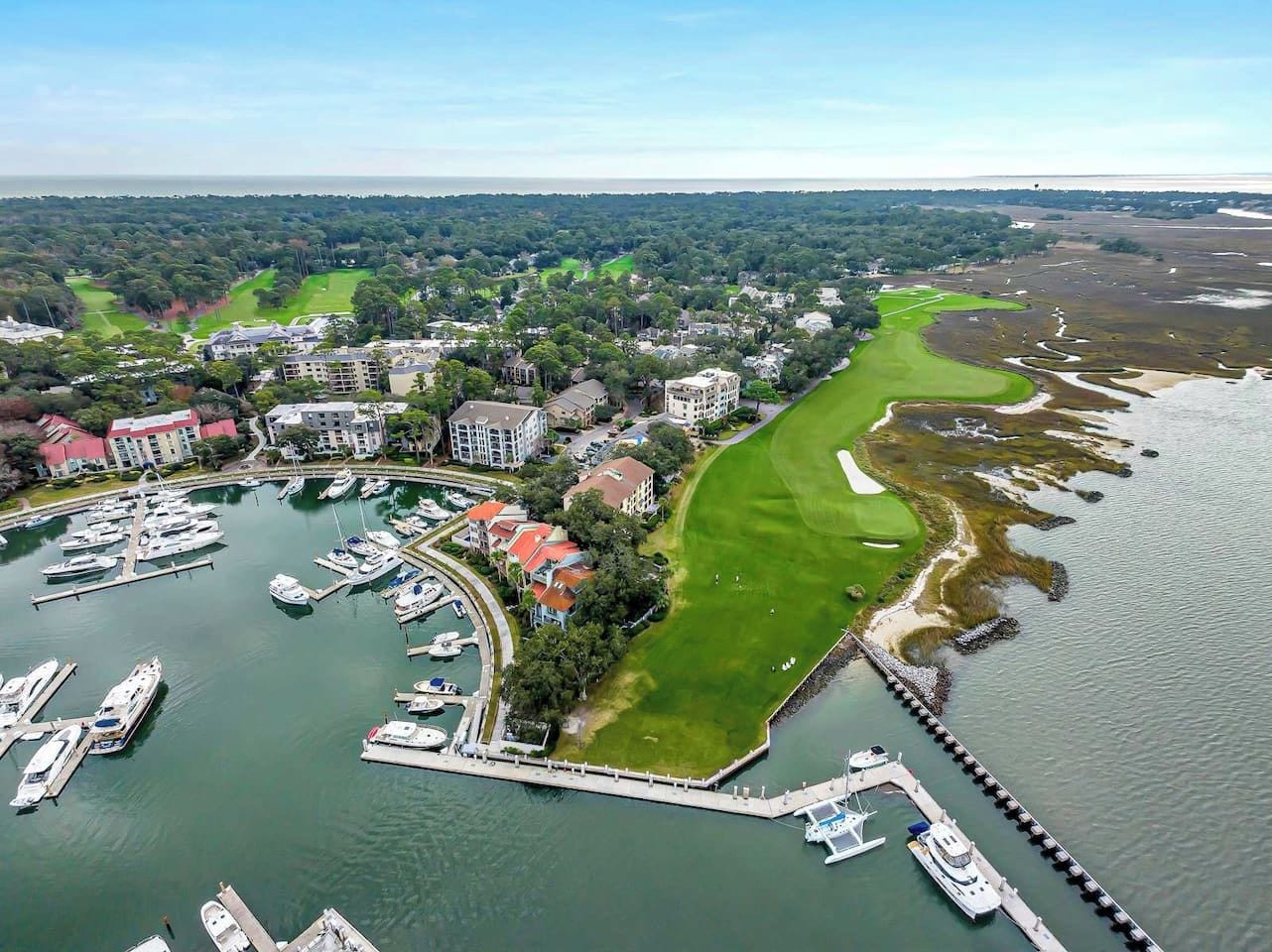 Vue aérienne d’une marina où sont amarrés des bateaux, d’un terrain de golf et des bâtiments environnants.