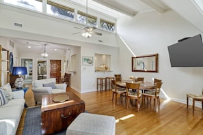 A spacious living area with a dining table, chairs, and a ceiling fan.