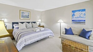 Quarto com cama, mesas de cabeceira, abajur, sofá e um quadro na parede.