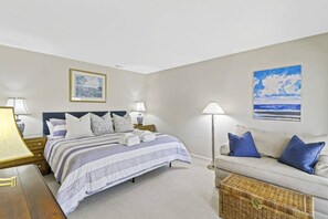 Une chambre à coucher avec un lit, des tables de chevet, une lampe, un canapé et un tableau au mur.