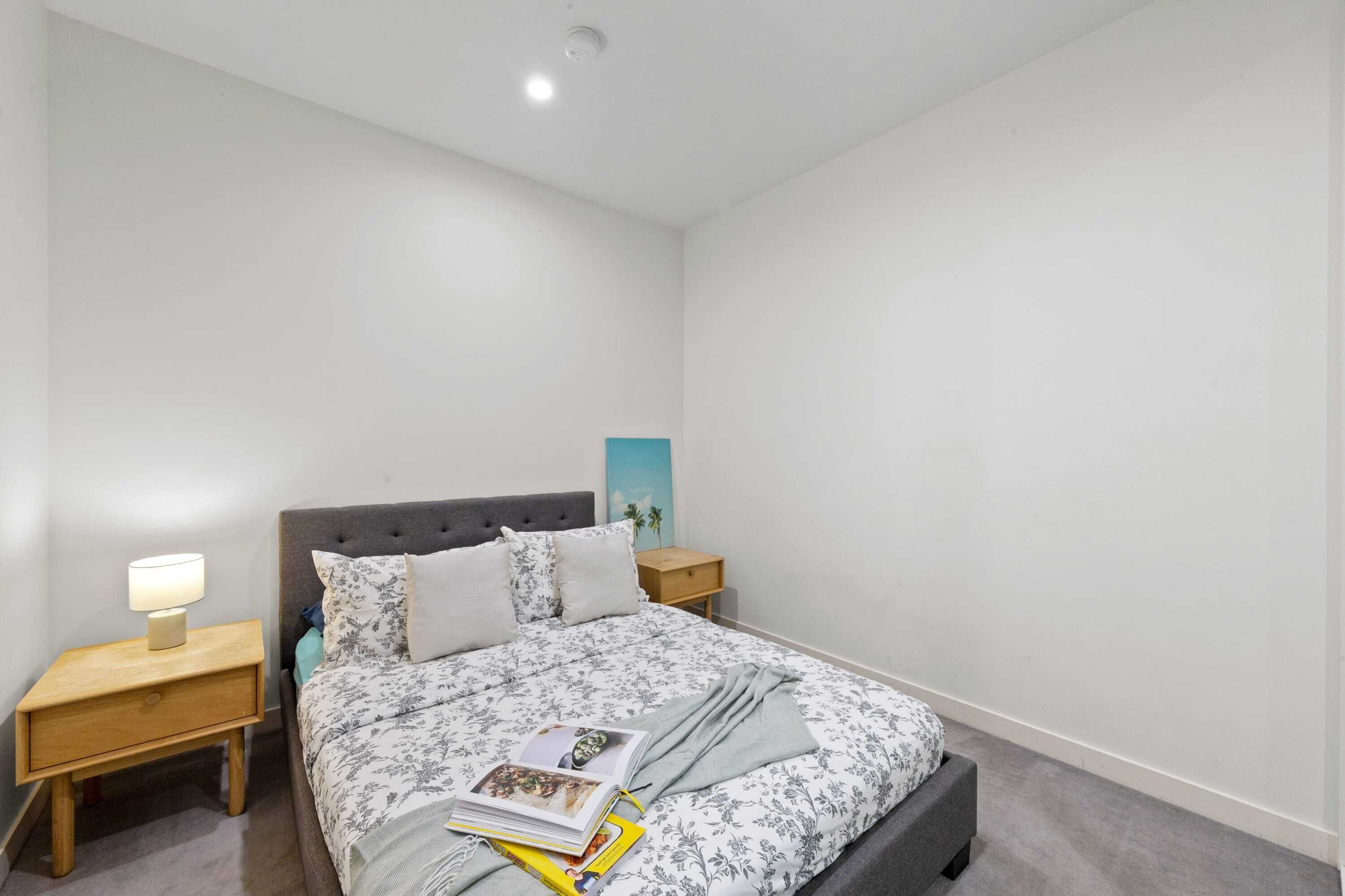 Una camera da letto con un letto, un comodino, una lampada e un quadro appeso al muro.