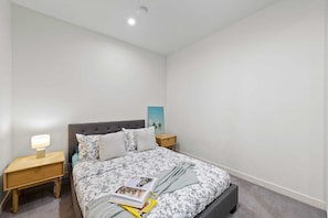 A bedroom with a bed, nightstands, a lamp, and a book.