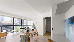 Eine moderne Wohnung mit Essbereich, Wohnzimmer mit Sofa und Couchtisch, und ein großes Fenster mit Blick auf die Stadt.