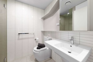 A modern bathroom with a white sink, toilet, and shower.