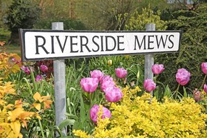A sign reading "RIVERSIDE Mews" surrounded by vibrant flowers. - Bakery Cottage, Thirsk (Thirsk)