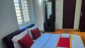 Una habitación de hotel con una cama grande, un armario, un espejo y una puerta.