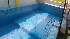 Una piscina interior con agua cristalina, una escalera y suelo de baldosas.