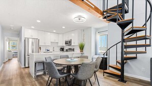 A modern kitchen with white cabinets, a central island, and a spiral staircase.