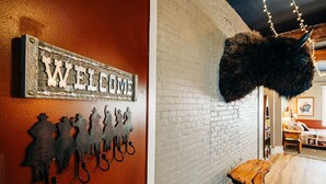 Ein rustikaler Innenraum mit einem 'WELCOME'-Schild, Metall-Silhouetten von Pferden und einem mit Fell bedeckten Gegenstand.