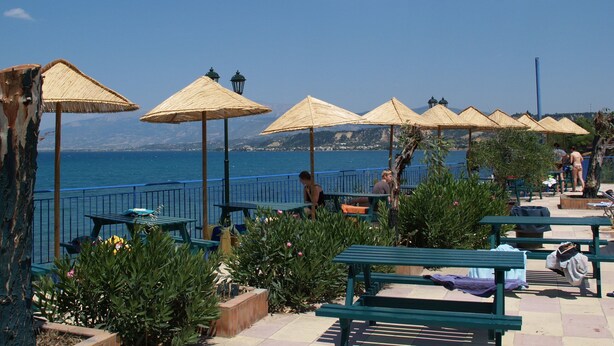 A seaside patio with outdoor seating and umbrellas, overlooking the sea. - Happy Camp in Camping Golden Sunset (West Achaea)