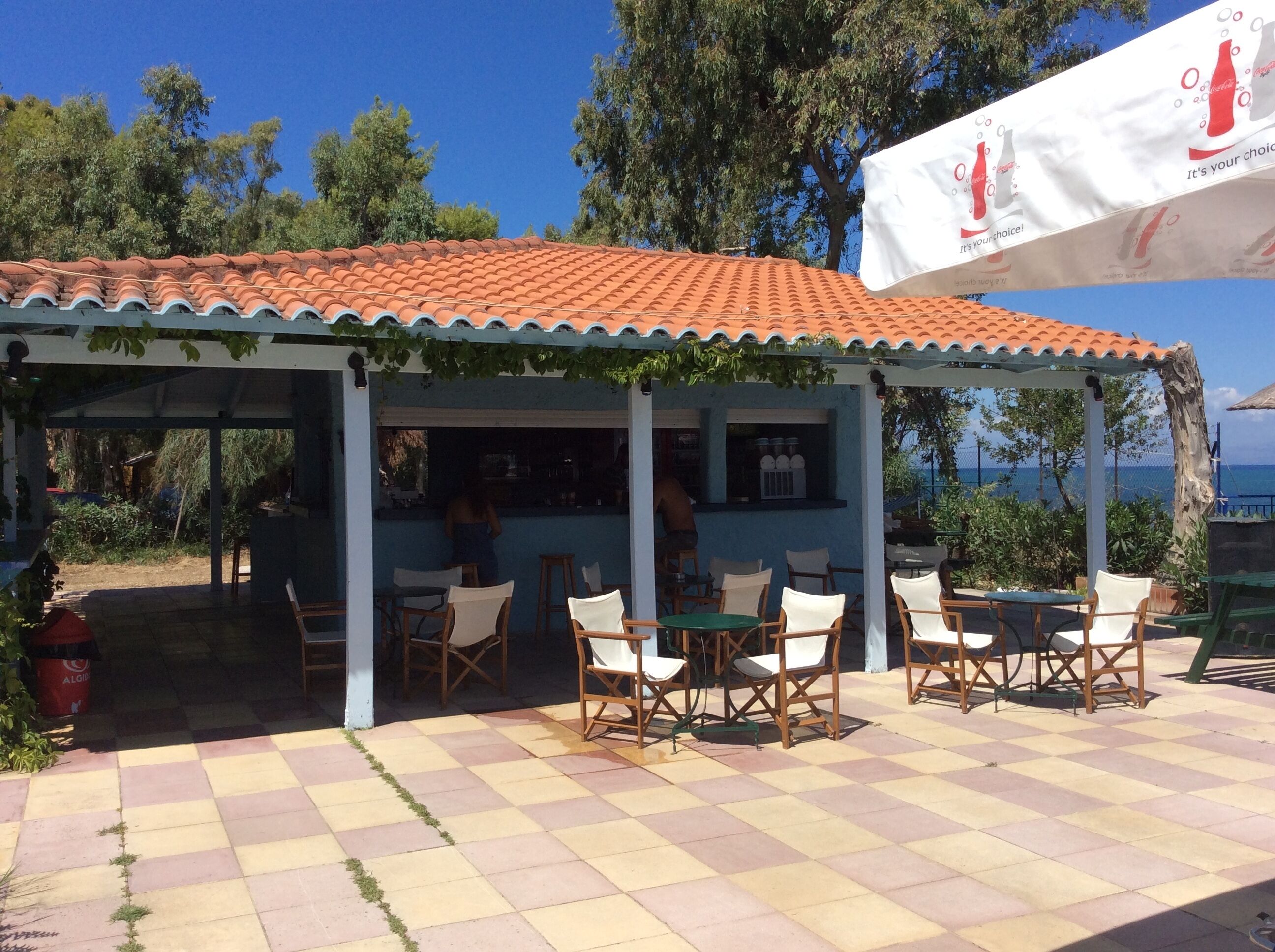 Un espace extérieur abrité, aménagé avec des tables et des chaises, un bar et offrant une vue sur la mer.