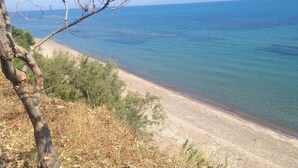 A coastal landscape with a sandy beach, clear blue sea, and sparse vegetation. - Happy Camp in Camping Golden Sunset (West Achaea)