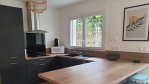 A modern kitchen with a wooden countertop, black cabinets, a built-in stove, and a window providing natural light. - Nouvelle Villa Provençale Calme, Proche du Centre (Montélimar)
