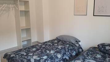 A bedroom with two beds, a wardrobe, and two framed motivational posters on the wall.