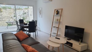 A modern living room with a sofa, coffee table, TV, and a dining area with chairs and a table. - Nouvelle Villa Provençale Calme, Proche du Centre (Montélimar)