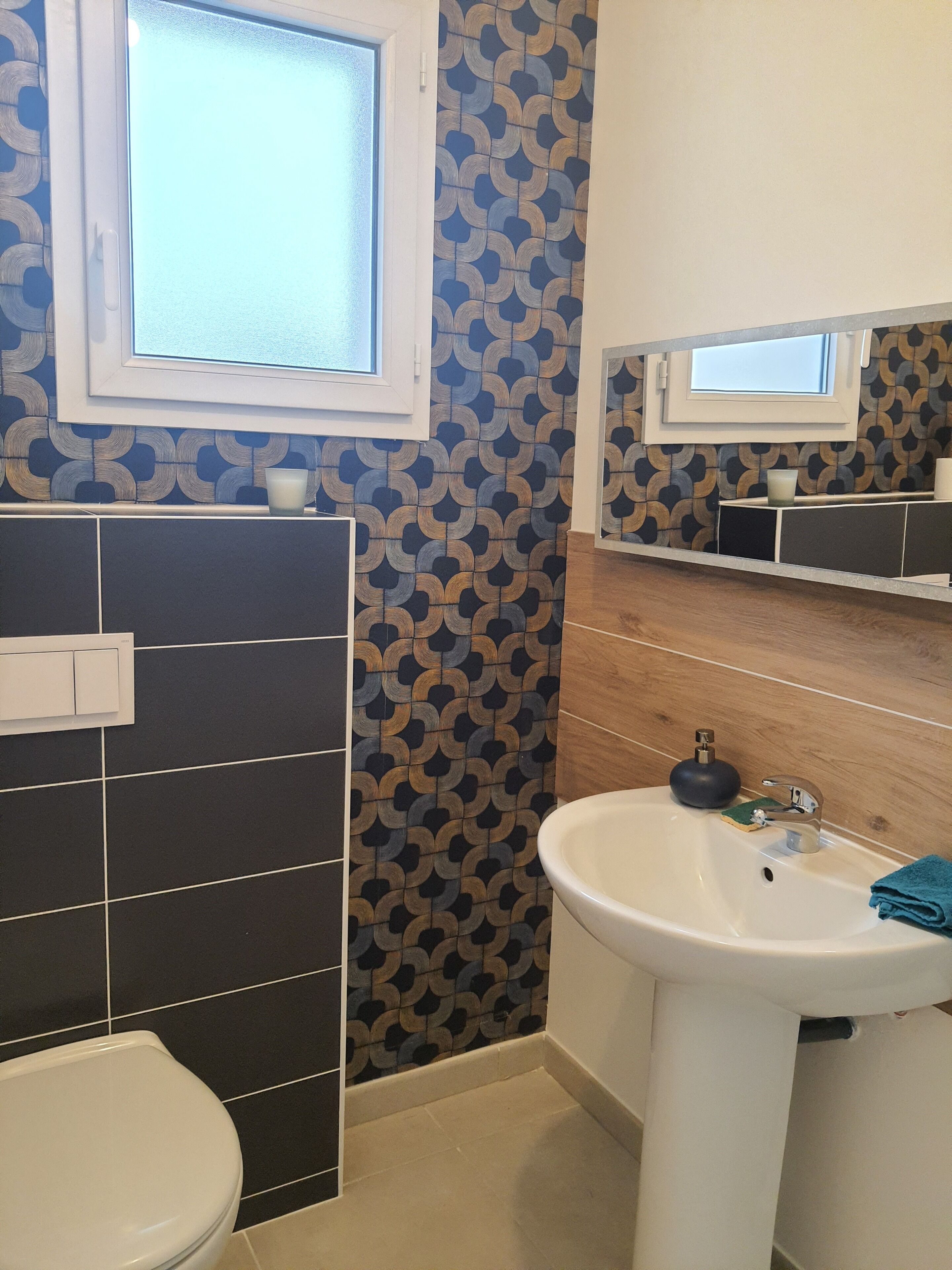 Een badkamer met toilet, wastafel en spiegel.