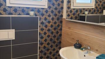 Een badkamer met toilet, wastafel en spiegel.