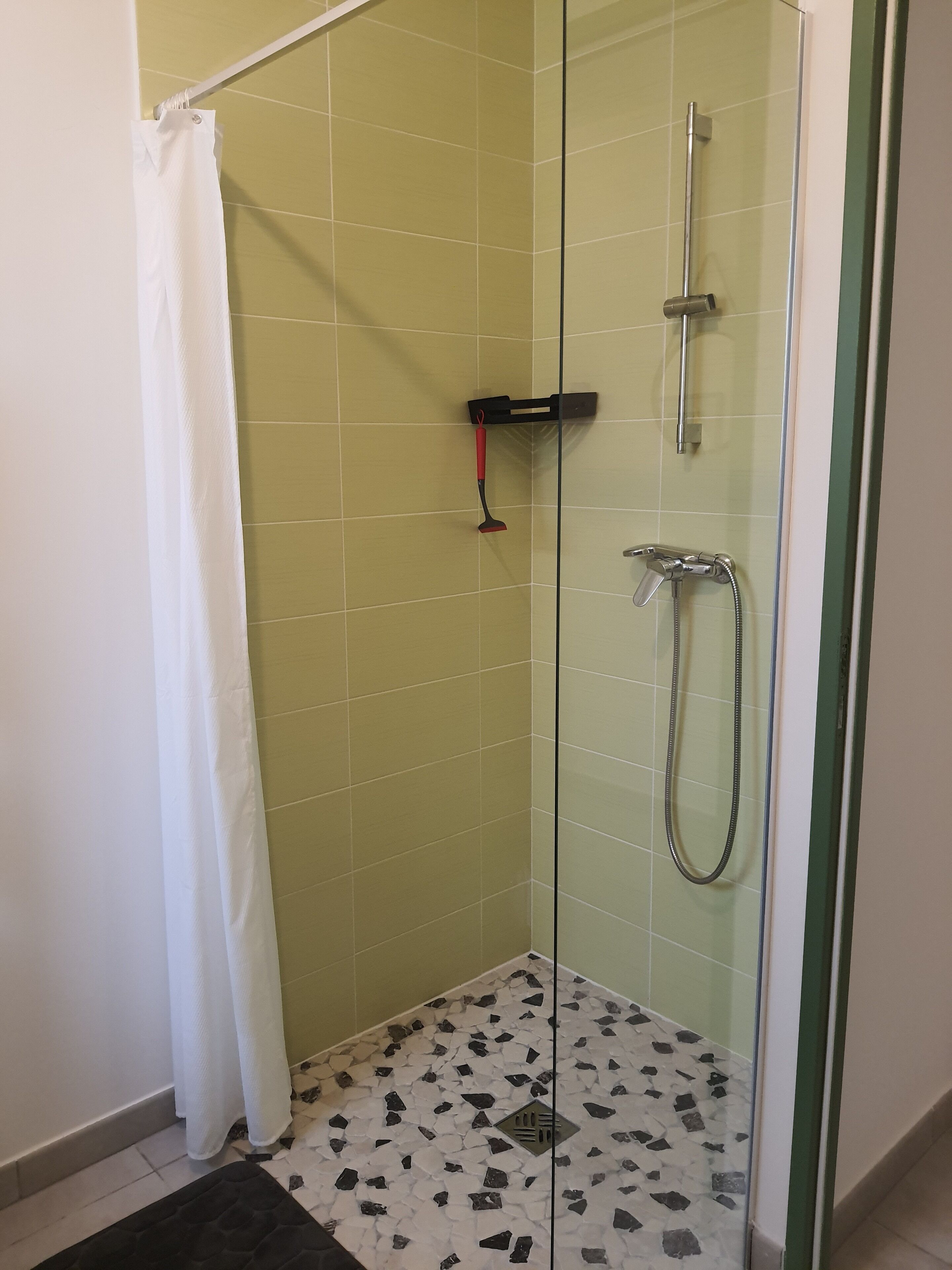 Et bruseområde med glasvægge, brusehoved, håndbruser og børste.