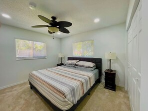 A bedroom with a bed, two bedside tables, a ceiling fan, and two windows with blinds. - 3 miles to Fort Myers Beach with king bed (Fort Myers Beach)