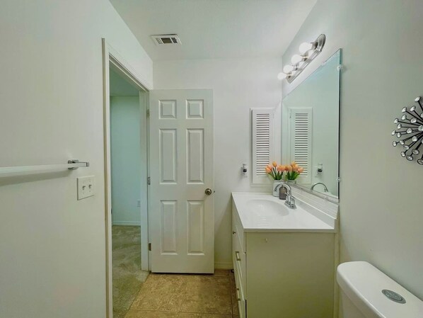A bathroom with a white door, a sink with a mirror, and a toilet.