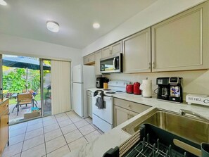 Cocina compacta con microondas, estufa y cafetera.