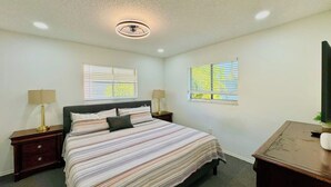 A bedroom with a single bed, two bedside tables with lamps, a ceiling fan, and two windows with blinds. - Near Fort Myers Beach • 2BR • 2BA • Grill (Fort Myers Beach)