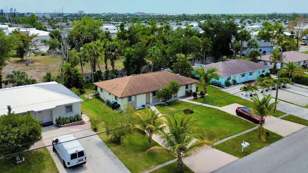 A residential area with houses, a white van, and a red car parked on the street. - Near Fort Myers Beach • 2BR • 2BA • Grill (Fort Myers Beach)