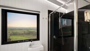 A bathroom with a window, a sink, and a glass-enclosed shower.