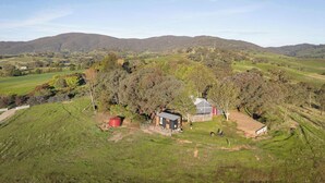 A rural landscape with a small building surrounded by trees and open fields.
